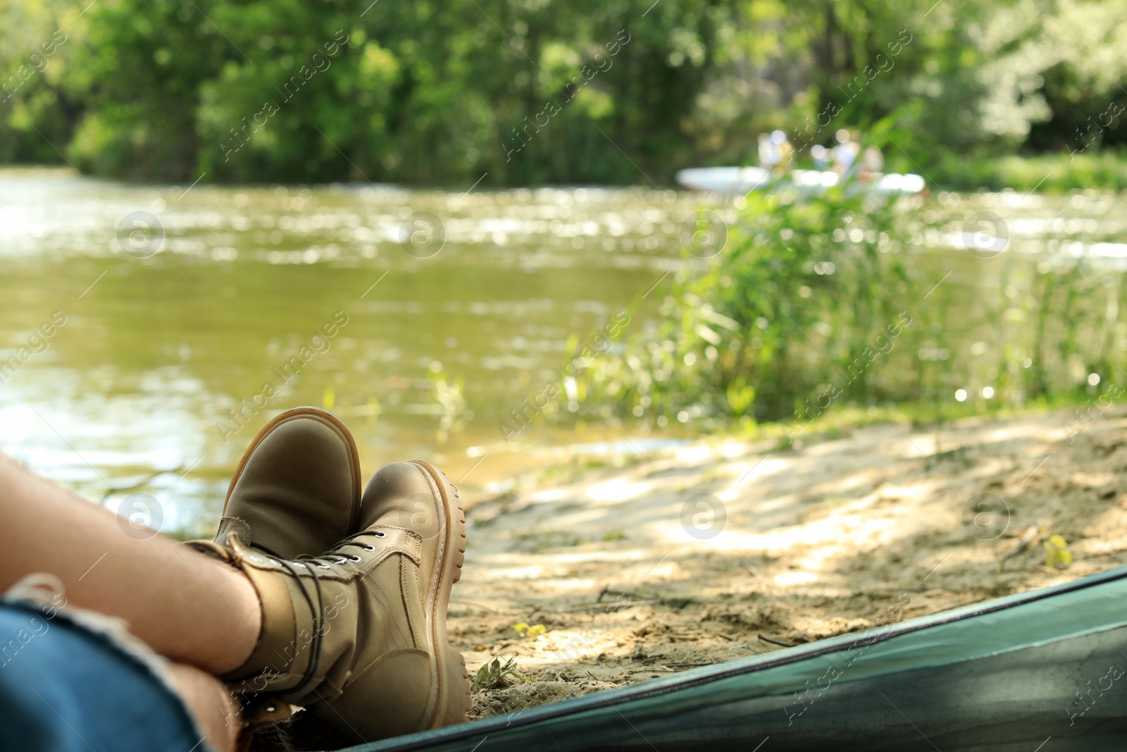 Photo of Young man resting in camping tent on riverbank, view from inside