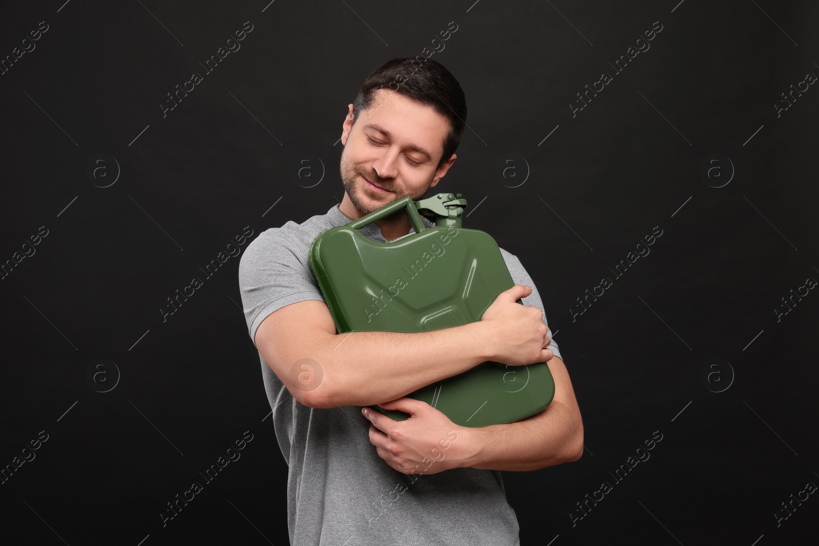 Photo of Handsome man holding khaki metal canister on black background