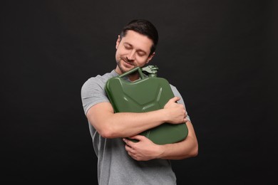 Handsome man holding khaki metal canister on black background