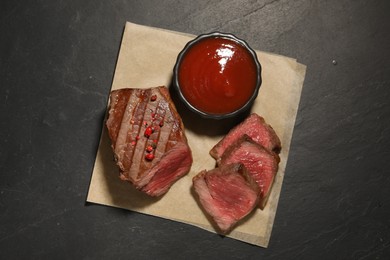 Delicious grilled beef steak with spices and tomato sauce on dark gray table, top view