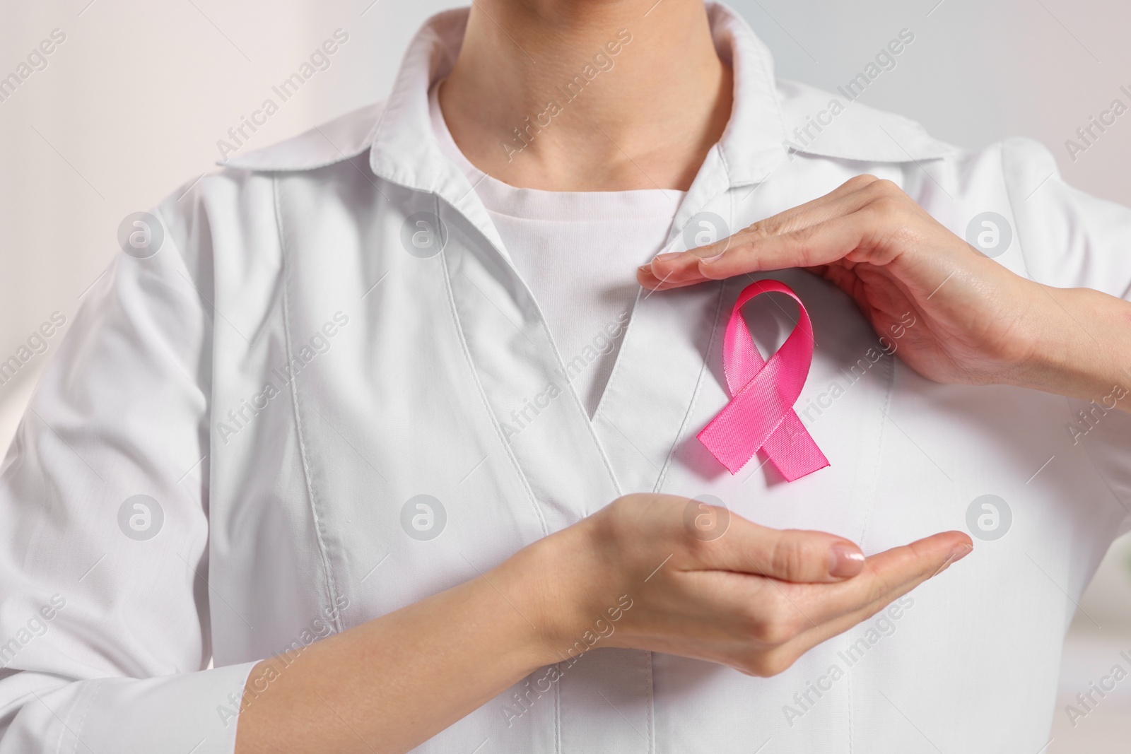 Photo of Mammologist with pink ribbon in hospital, closeup. Breast cancer awareness