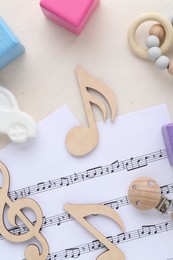 Photo of Wooden notes, music sheets and toys on beige background, flat lay. Baby song concept