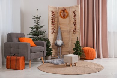 Photo of Beautiful Christmas themed photo zone with trees, dwarf and armchair in room