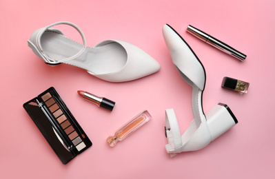 Photo of Stylish white female shoes and decorative cosmetics on pink background, flat lay