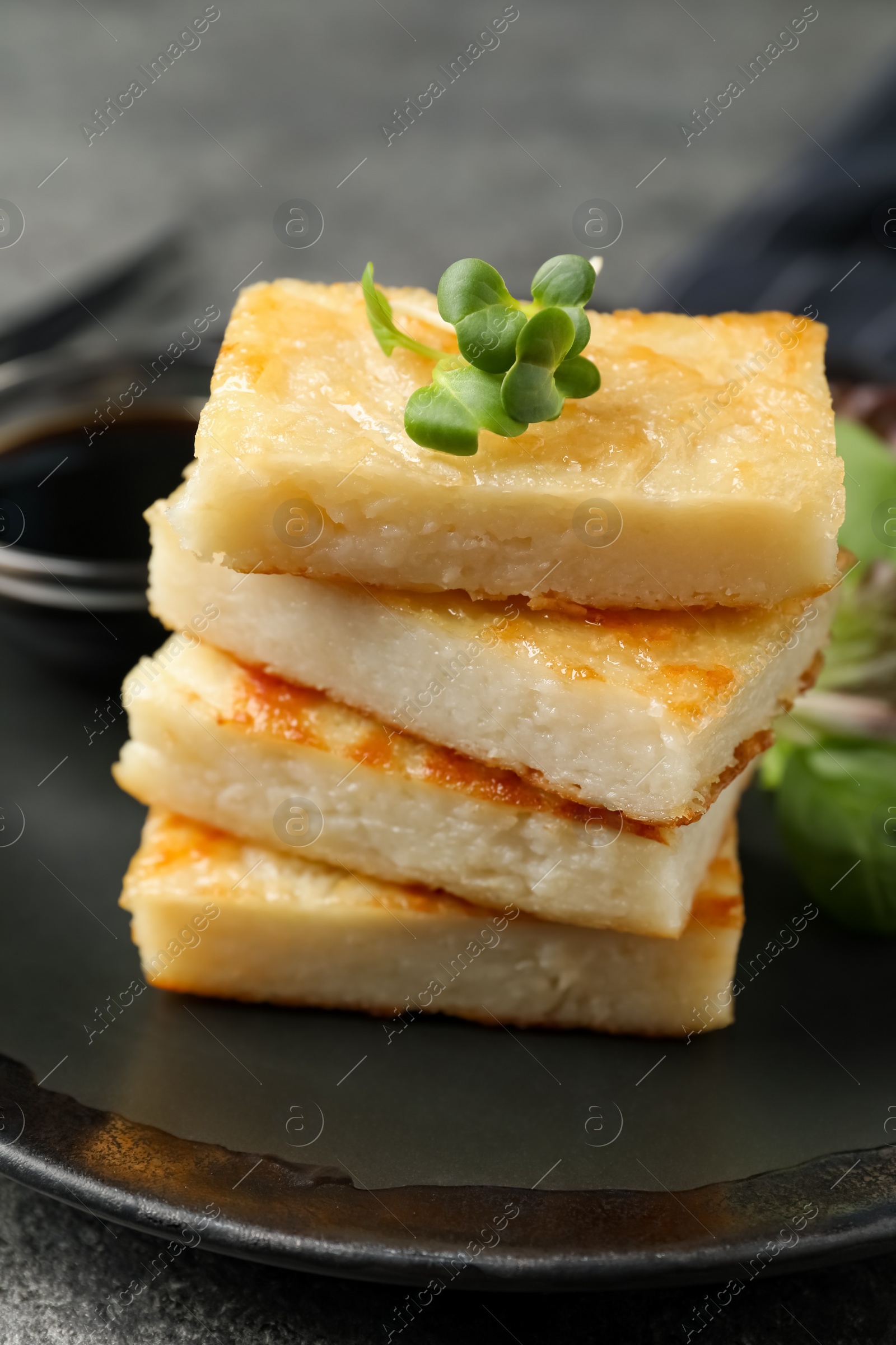 Photo of Delicious turnip cake with herbs served on grey table, closeup