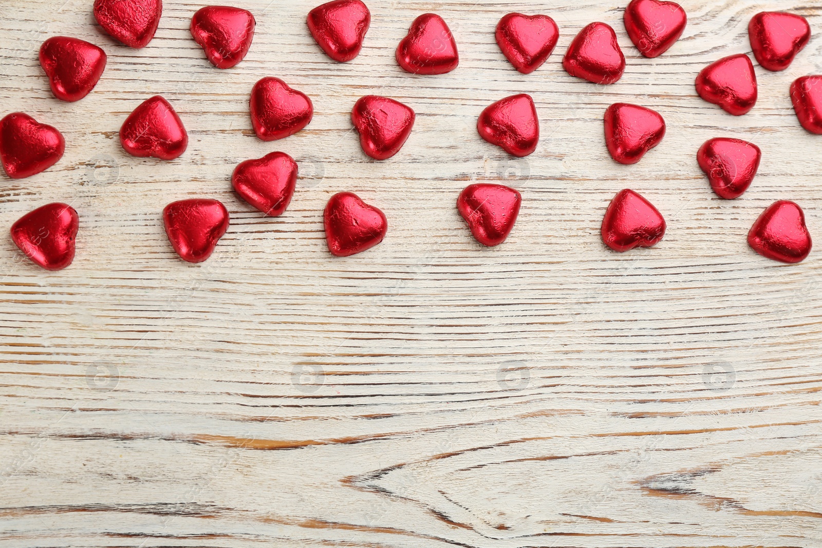 Photo of Heart shaped chocolate candies on white wooden table, flat lay with space for text. Valentines's day celebration