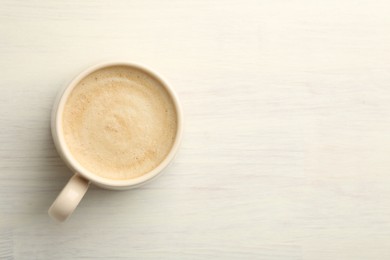 Photo of Cup of coffee on white wooden table, top view. Space for text