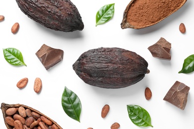 Photo of Cocoa pods with beans, powder and chocolate pieces on white background, top view