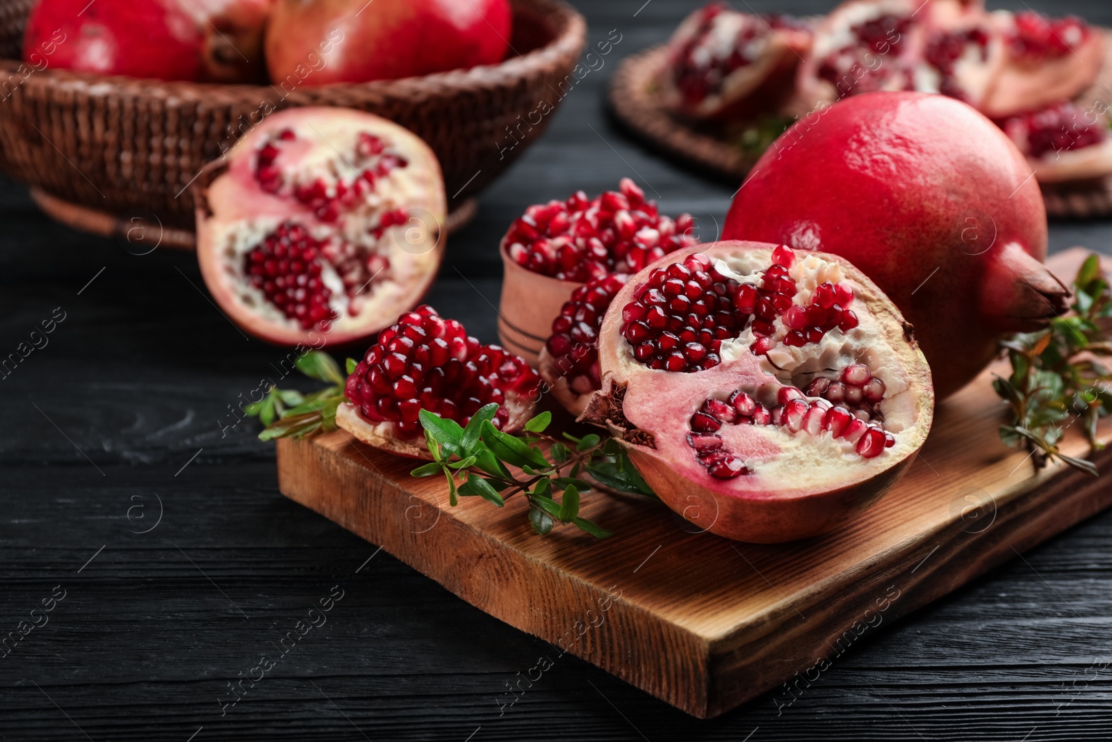 Photo of Delicious ripe pomegranates on black wooden table