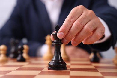 Photo of Man with king game piece playing chess at checkerboard, closeup