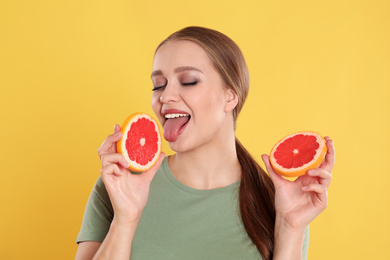 Photo of Young woman with cut grapefruit on yellow background. Vitamin rich food