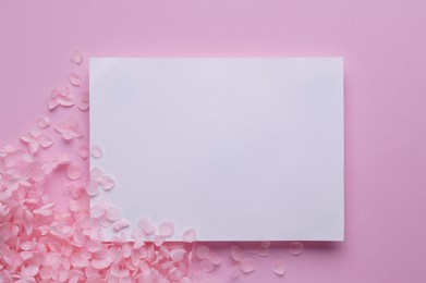 Beautiful hortensia flowers and sheet of paper on pink background, flat lay. Space for text