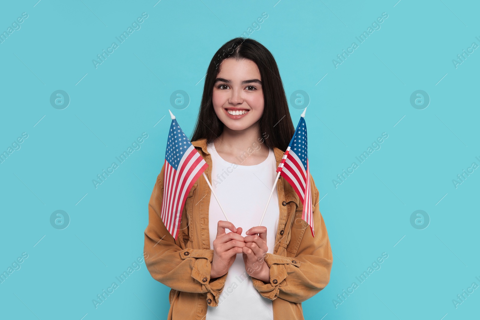 Photo of 4th of July - Independence Day of USA. Happy girl with American flags on light blue background