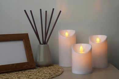 Photo of Glowing decorative LED candles on wooden table indoors