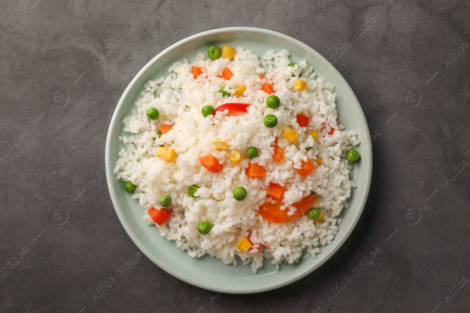 Photo of Delicious rice with vegetables on grey table, top view