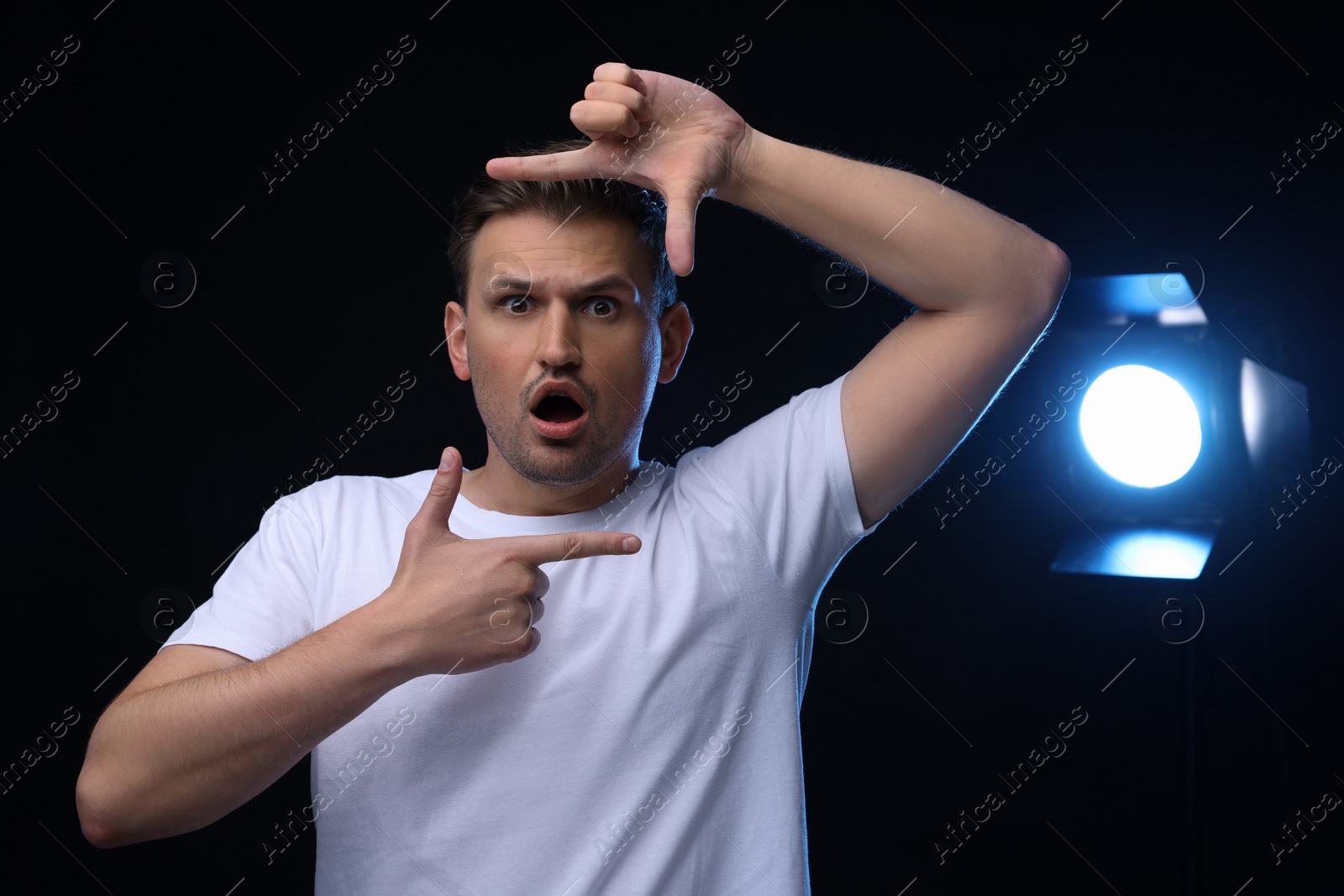 Photo of Casting call. Emotional man showing frame gesture on black background