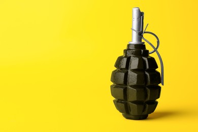 Photo of Hand grenade on yellow background. Space for text