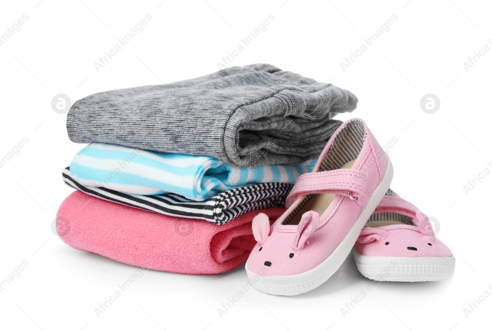 Photo of Children's shoes and stack of clothes on white background