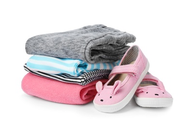 Photo of Children's shoes and stack of clothes on white background