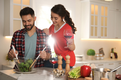 Photo of Lovely young couple cooking salad together in kitchen