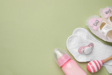 Flat lay composition with pacifier and other baby stuff on pale green background. Space for text