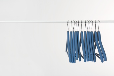 Metal rack with clothes hangers on white background, space for text