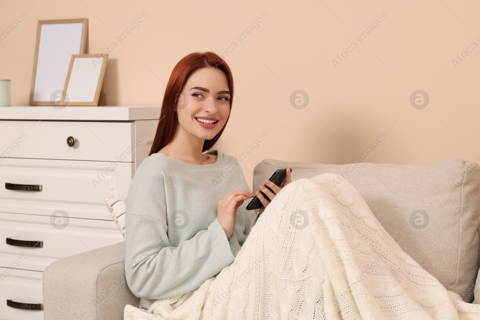 Photo of Happy woman with red dyed hair using smartphone at home