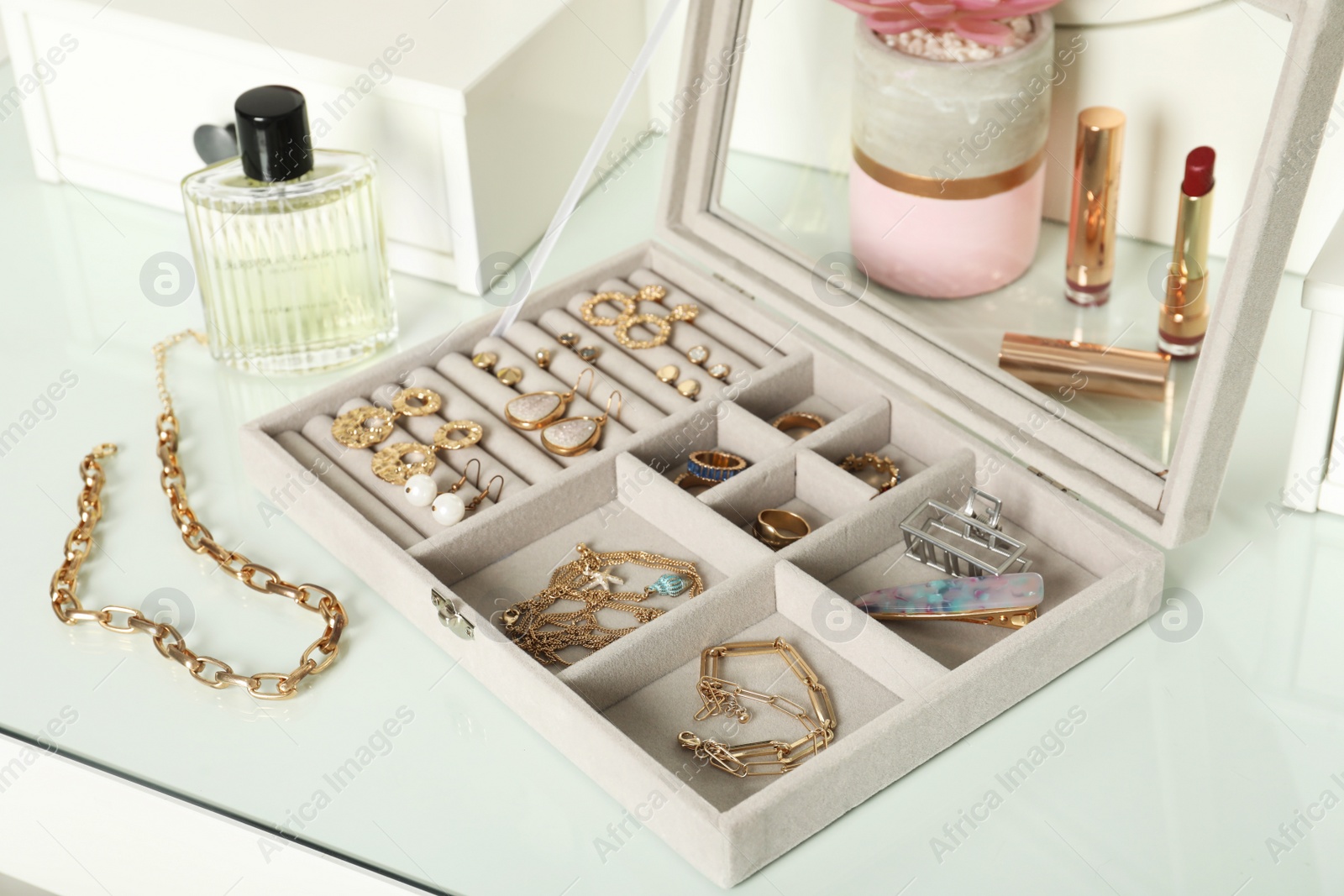 Photo of Elegant jewelry box with beautiful bijouterie, cosmetics and perfume on dressing table