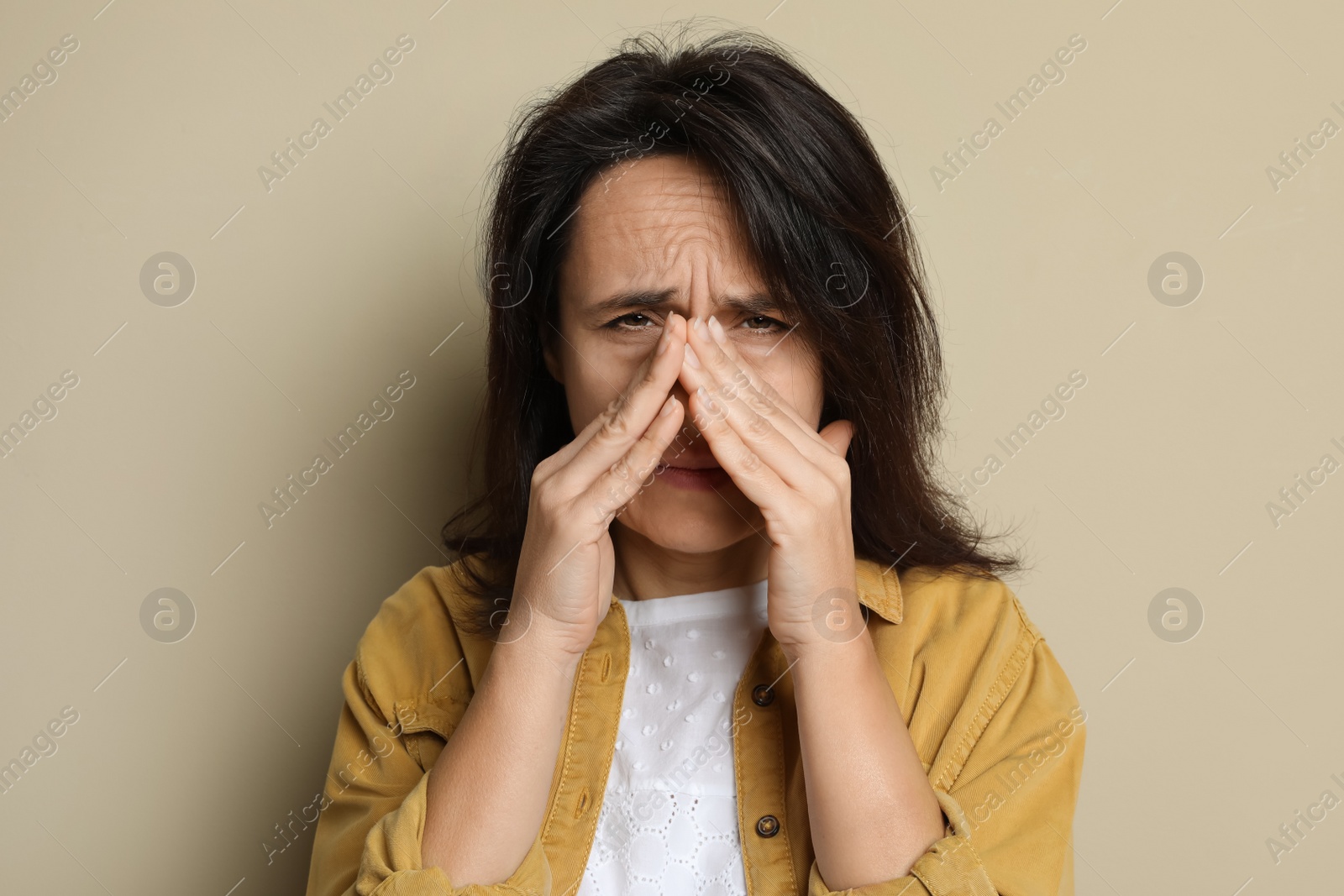 Photo of Mature woman suffering from headache on beige background