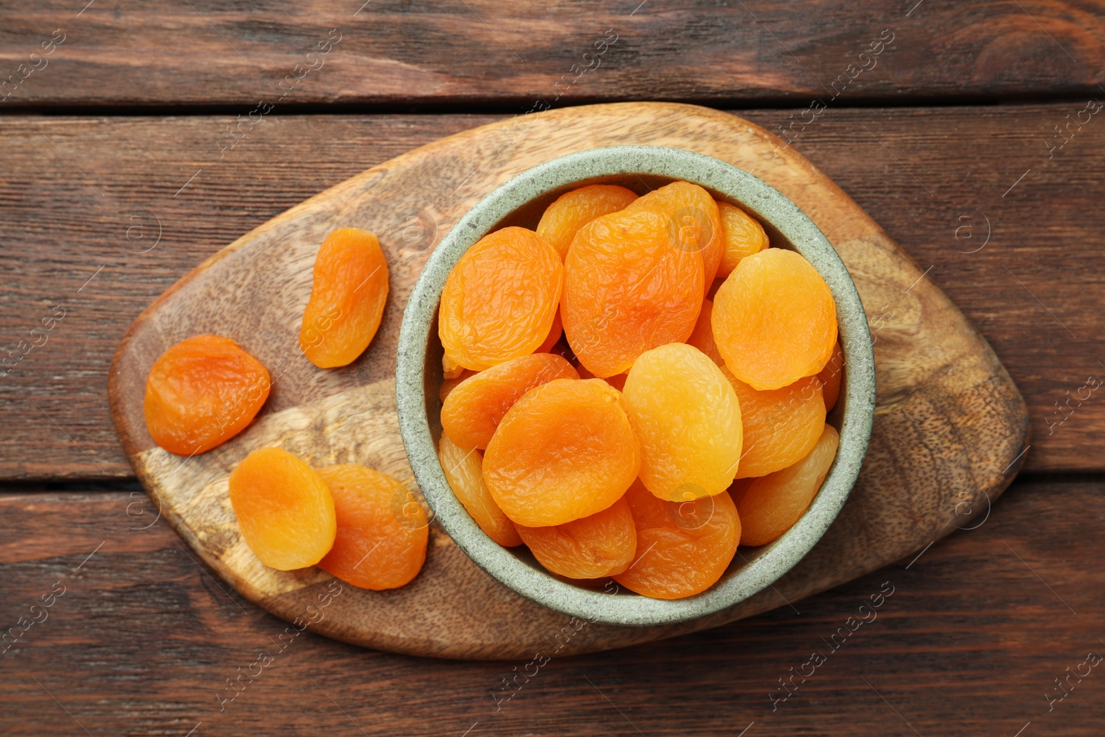 Photo of Bowl of tasty apricots on wooden table, top view. Dried fruits
