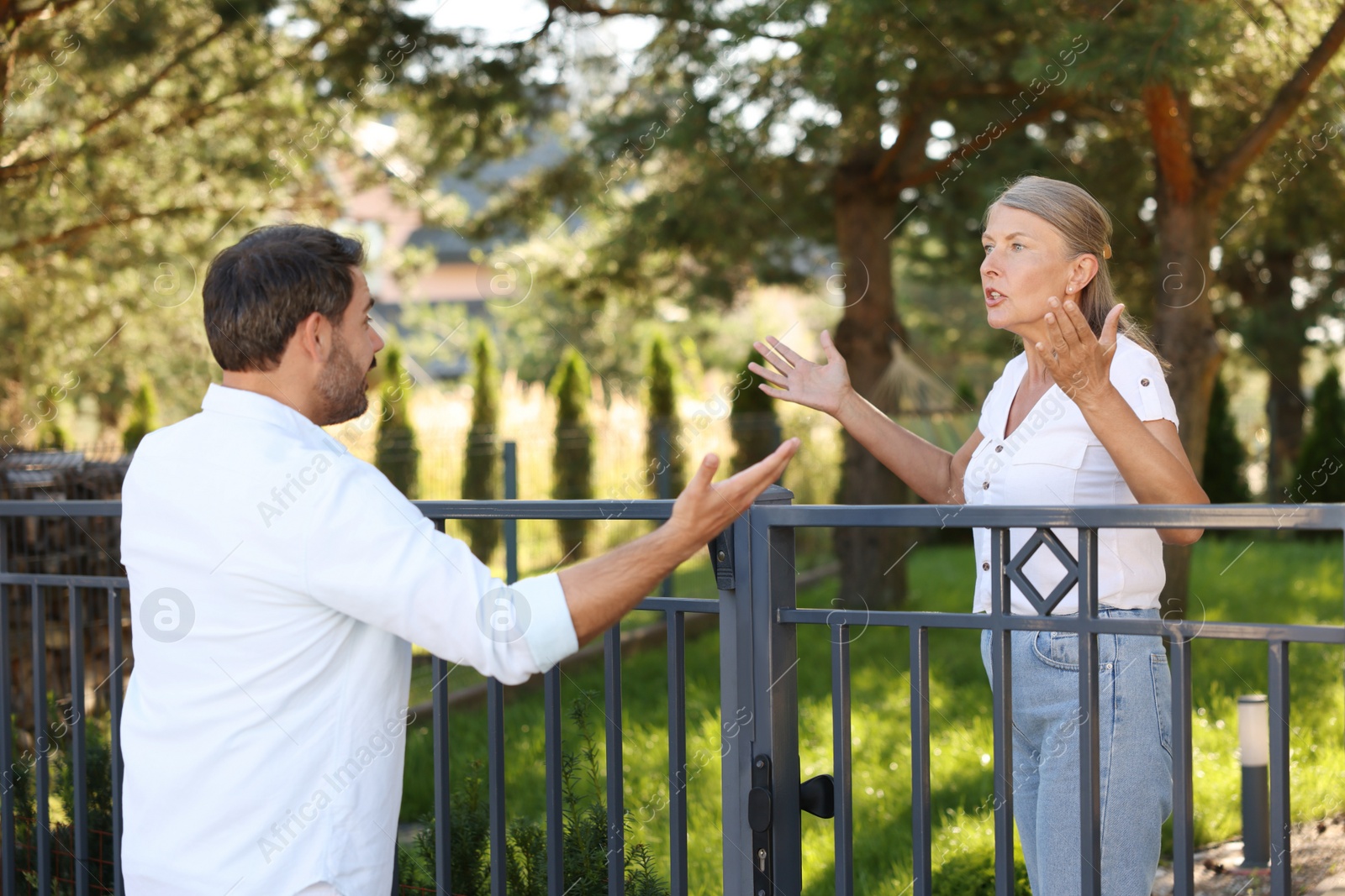 Photo of Emotional neighbours having argument near fence outdoors