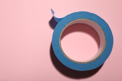 Photo of Roll of light blue adhesive tape on pink background, top view. Space for text