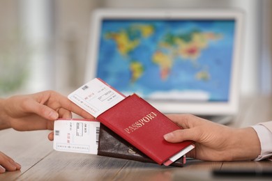 Photo of Travel agent giving tickets and passports to client in office, closeup