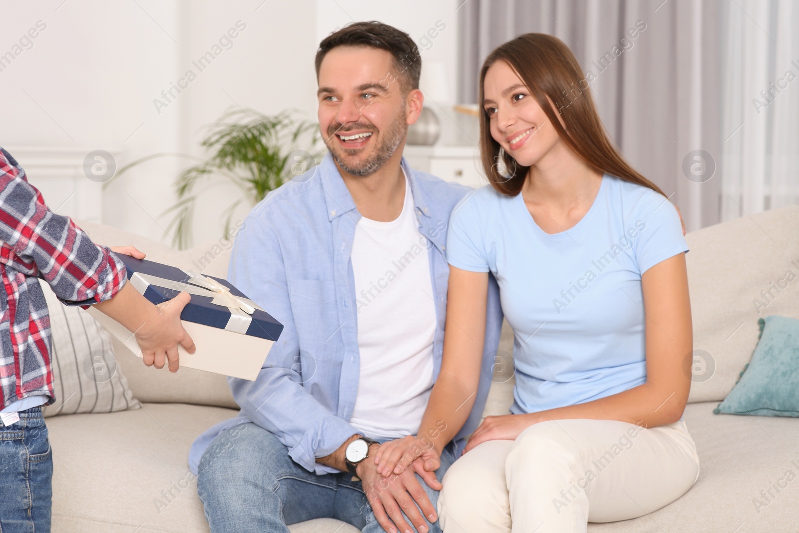 Photo of Little boy presenting his parents with gift at home