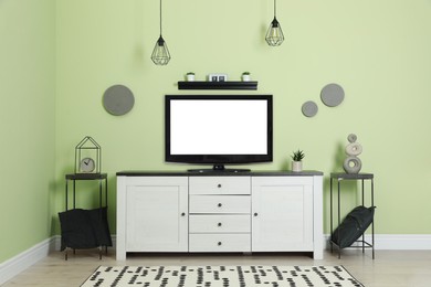 Photo of Modern TV set near green wall in living room