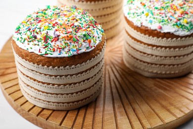 Photo of Traditional Easter cakes with sprinkles on white wooden table, closeup