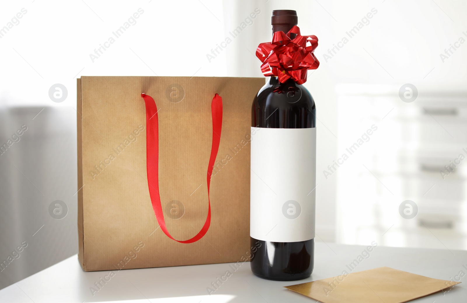 Photo of Bottle of wine, card and paper bag on table in light room