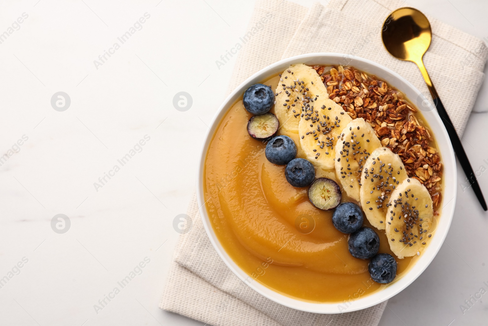 Photo of Delicious smoothie bowl with fresh blueberries, banana and granola on white table, flat lay. Space for text