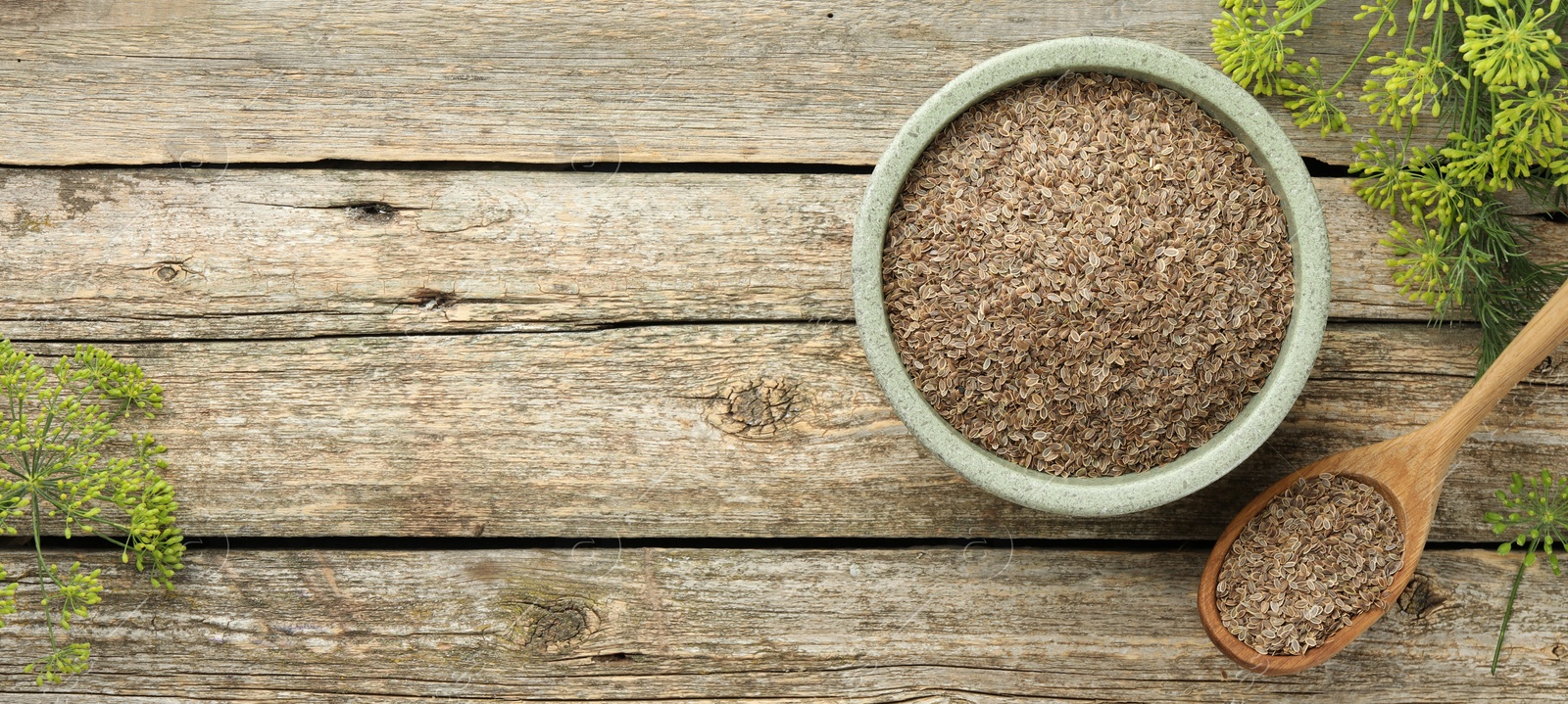 Image of Dill seeds in spoon and bowl on wooden table, flat lay. Banner design with space for text