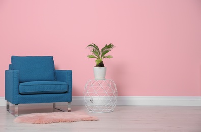Comfortable armchair near color wall. Modern interior element