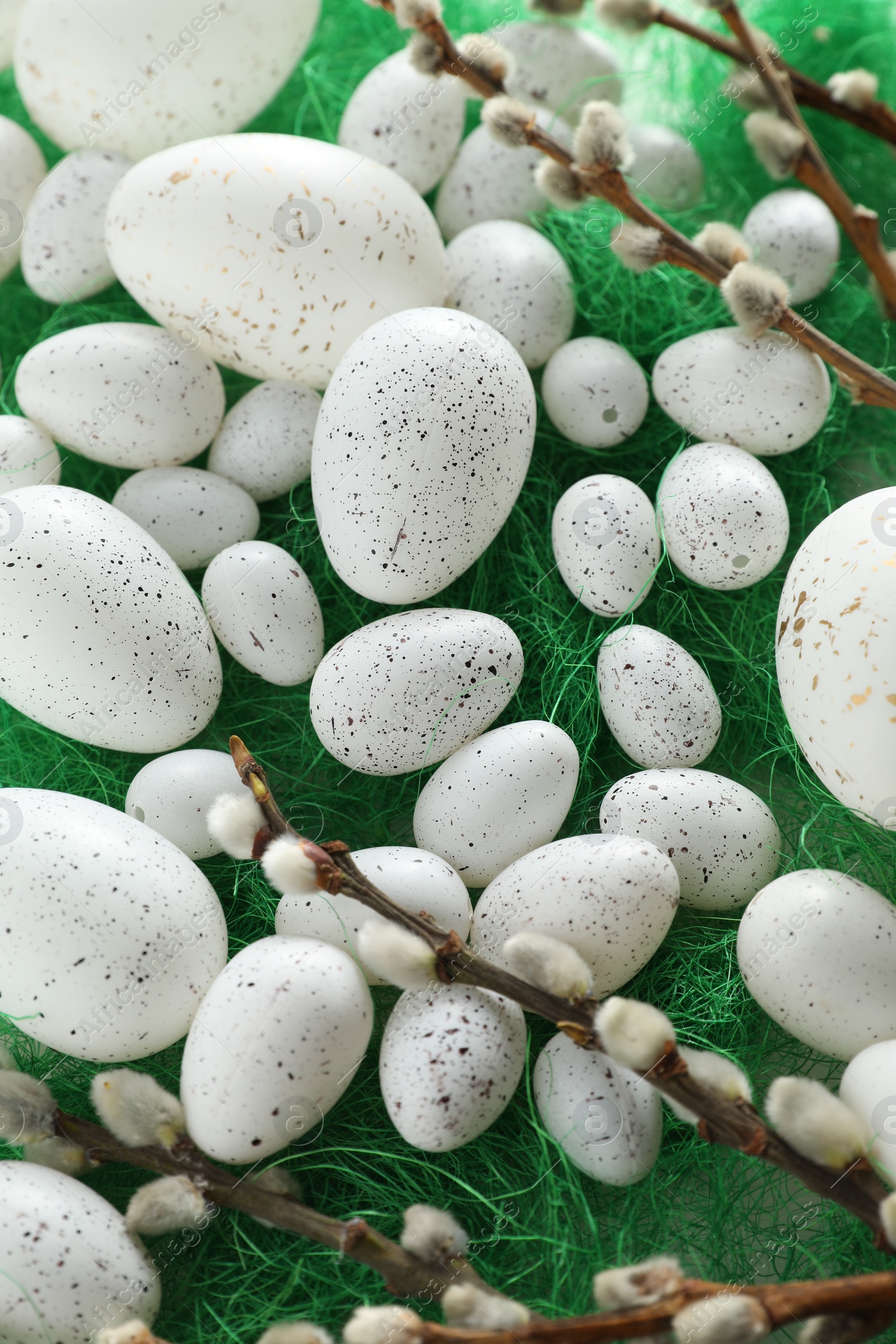 Photo of Many beautifully painted Easter eggs and pussy willow branches on green background