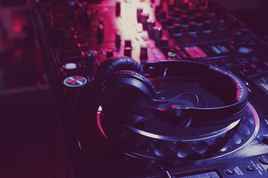 Photo of Closeup view of modern DJ controller with headphones on dark background