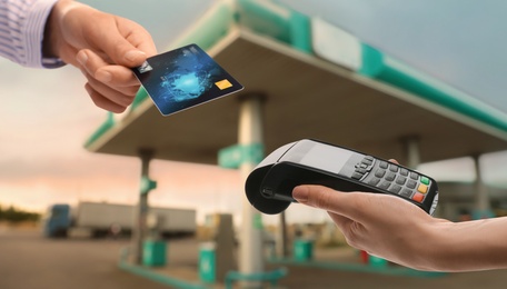 Image of Woman paying for fuel using credit card via payment terminal at gas station, closeup