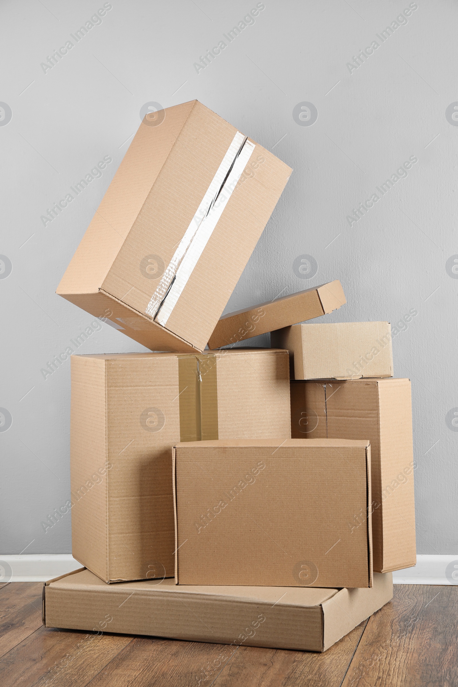 Photo of Pile of cardboard boxes near light blue wall indoors