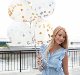 Photo of Beautiful young woman with bunch of balloons outdoors