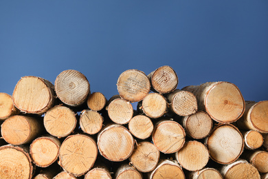 Photo of Cut firewood on blue background. Heating in winter