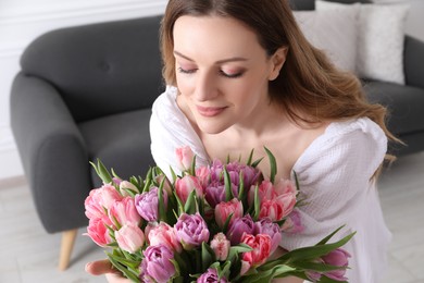 Young woman with bouquet of beautiful tulips indoors
