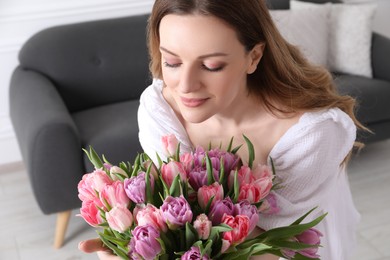 Photo of Young woman with bouquet of beautiful tulips indoors