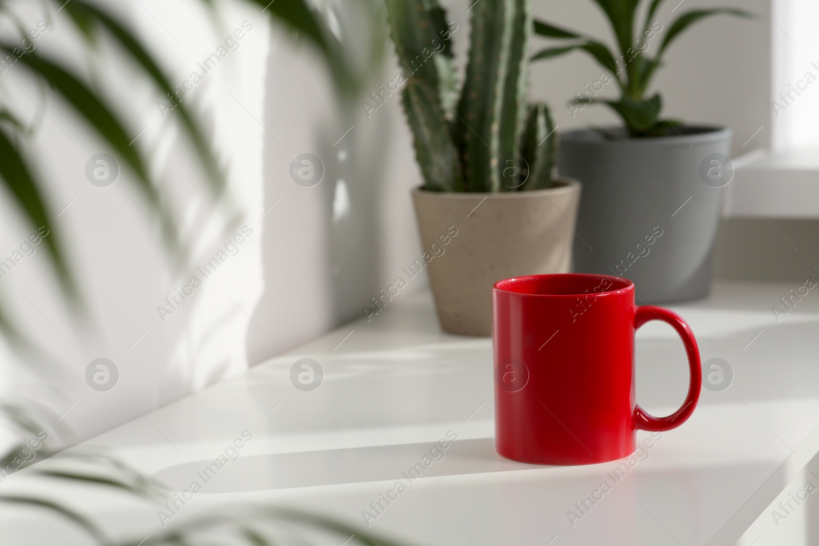 Photo of Red ceramic mug on white table indoors. Mockup for design