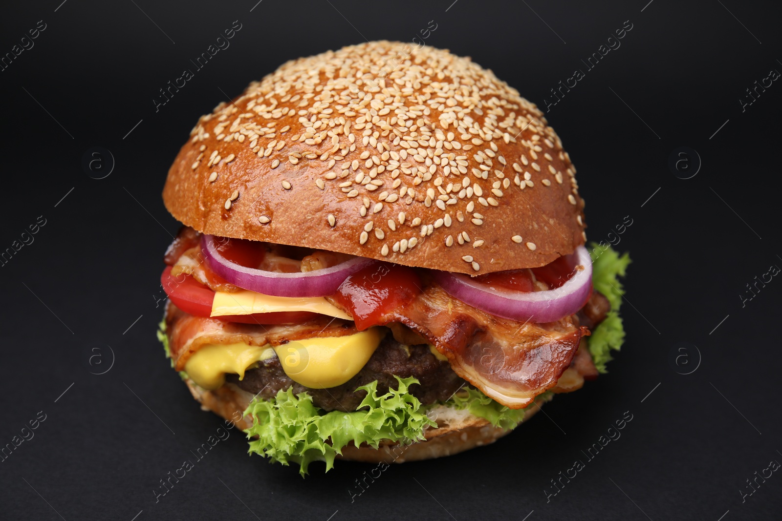 Photo of Delicious burger with bacon, patty and vegetables on black background, closeup